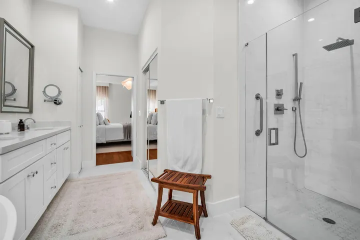 Modern bathroom featuring a frameless glass shower enclosure with a rainfall showerhead and hand sprayer