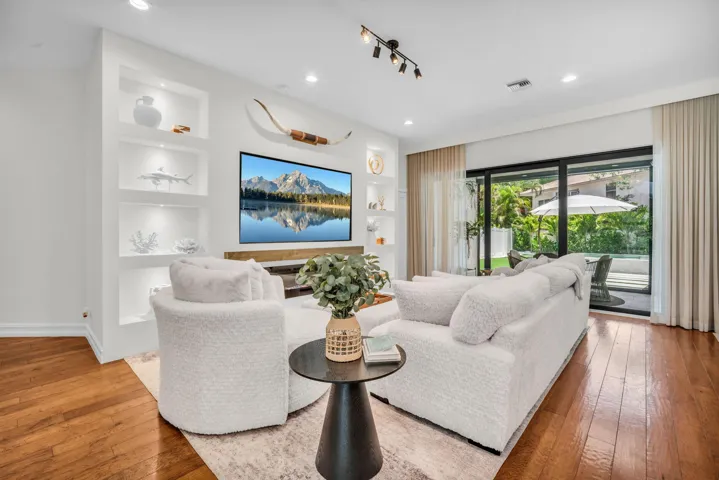 Living area featuring wood-finish flooring, recessed lighting, and built-in shelving with integrated illumination