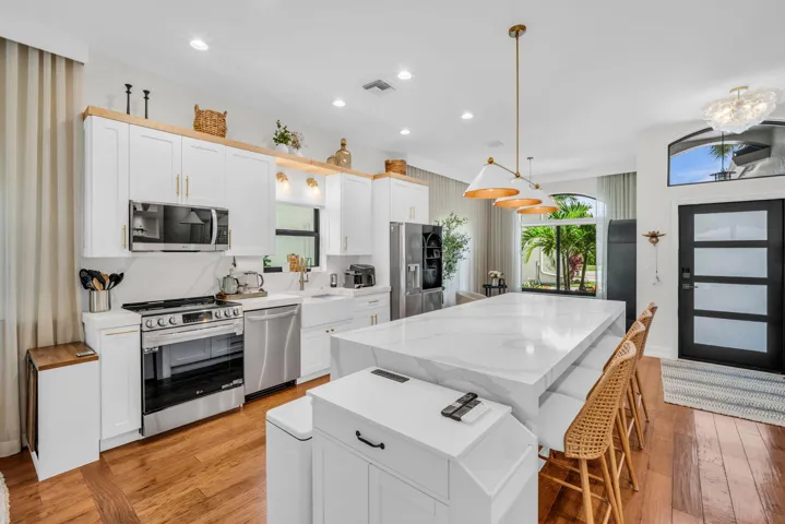 Kitchen with wood-finish flooring and a large waterfall island featuring a stone-look countertop