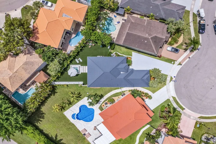 Contemporary-style home featuring a dark gray roof, a spacious driveway, and a private rear yard with a spa
