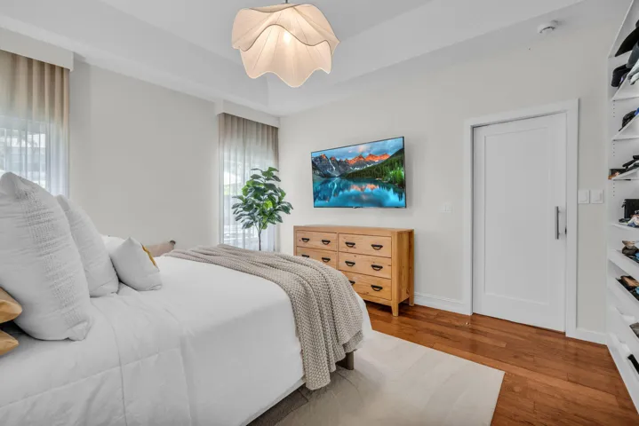 Bedroom featuring warm wood-finish flooring, a contemporary ceiling fixture, and a built-in shelving unit