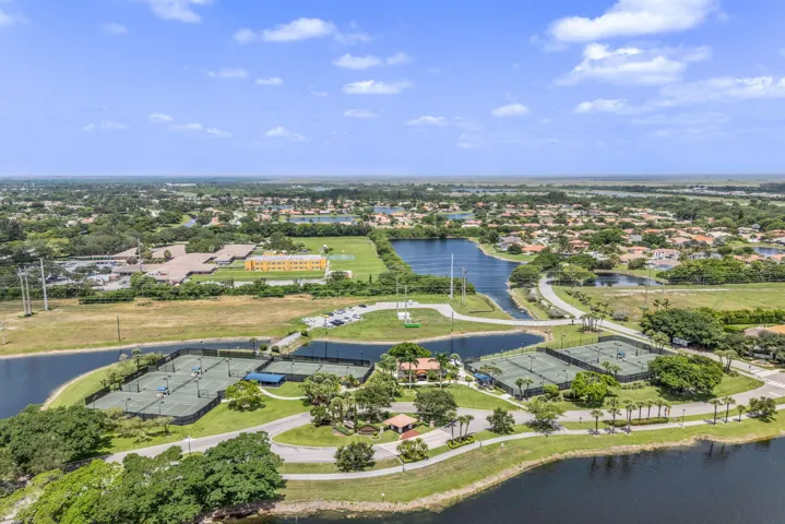 Aerial perspective showcasing multiple tennis courts, surrounding waterways, and a residential community