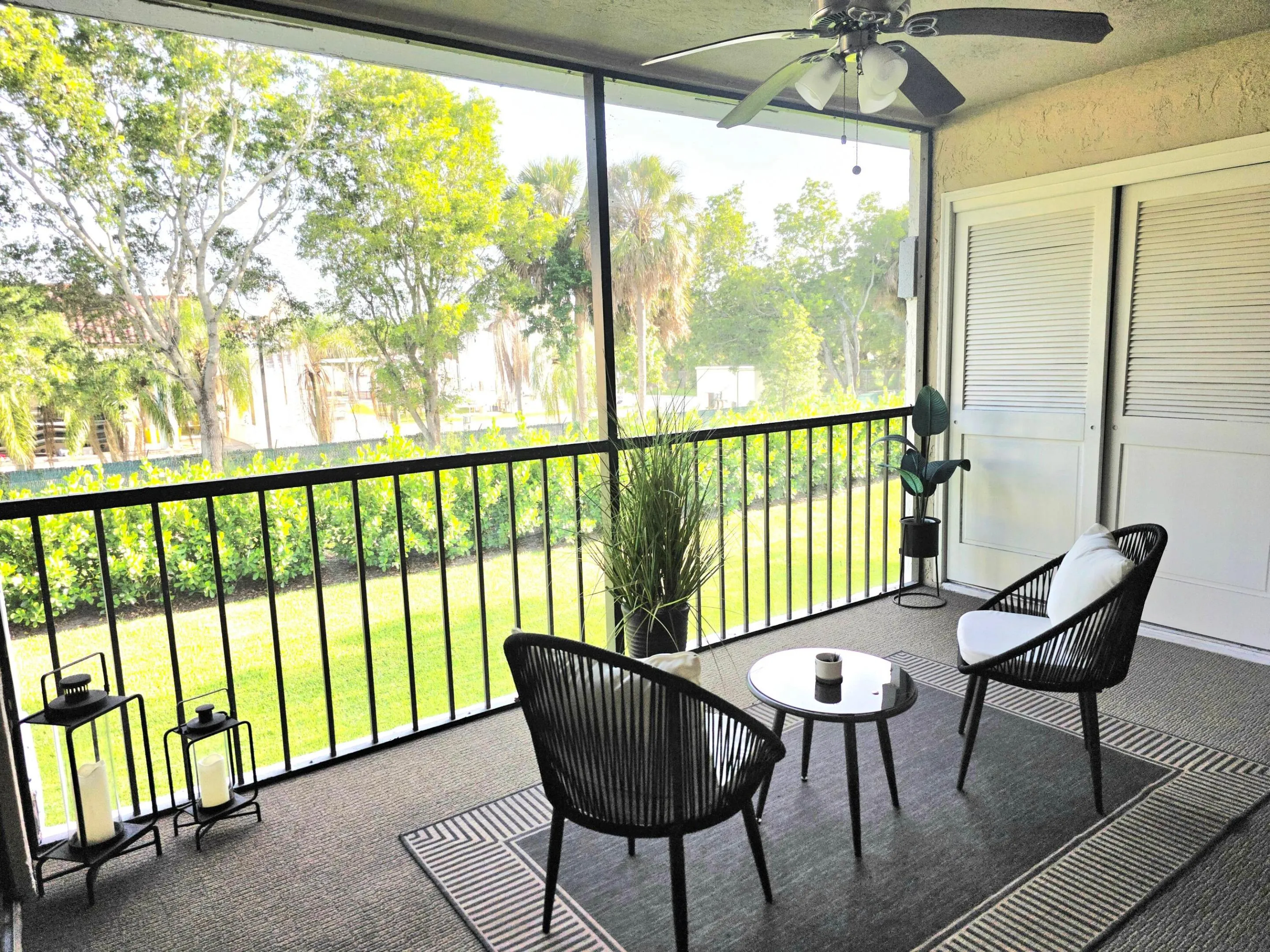 Screened in and covered balcony with ceiling fan and lights.