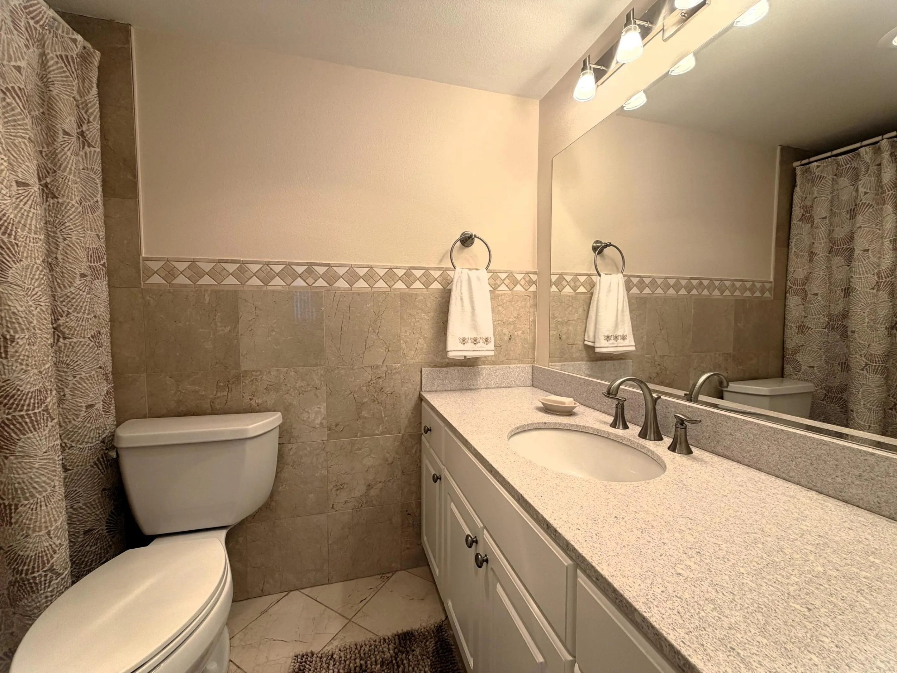 Bathroom featuring a white vanity with an integrated sink, a speckled countertop, and brushed nickel fixtures