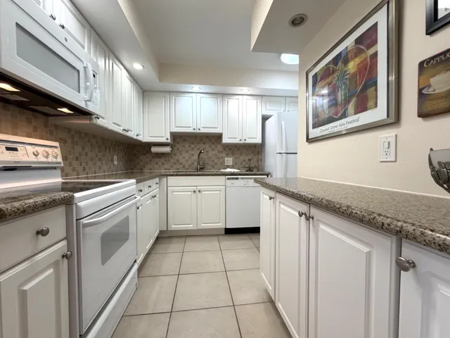 Kitchen featuring white cabinetry, speckled countertops, stainless steel sink, tiled backsplash, and recessed lighting