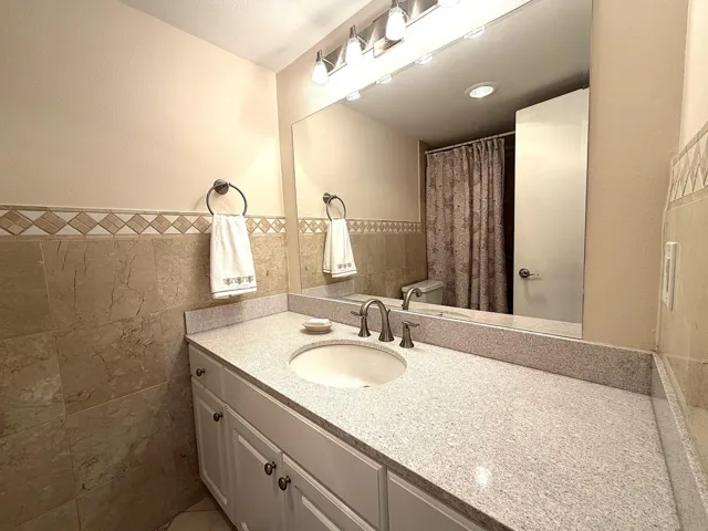 Bathroom vanity featuring a light-toned countertop, an undermount sink, and a brushed nickel faucet