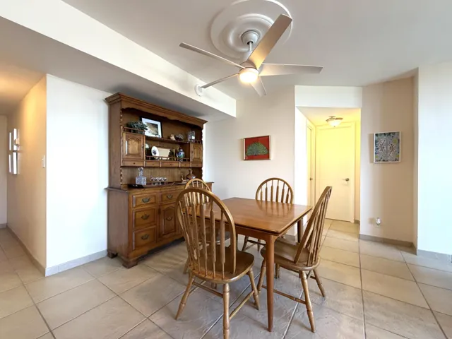 Dining area featuring neutral-toned tile flooring, a ceiling fan with light fixture, and a built-in wood hutch with display shelving