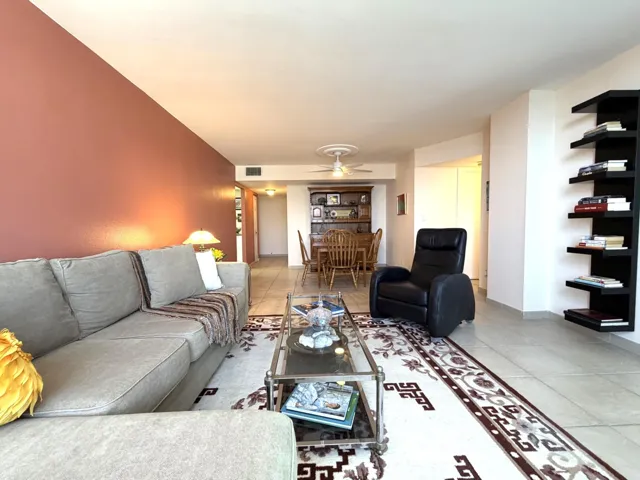 Open-concept living space featuring tile flooring throughout, a ceiling fan with integrated lighting, and a distinctive accent wall