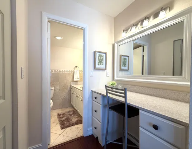 Integrated vanity space featuring a wide mirror with overhead lighting