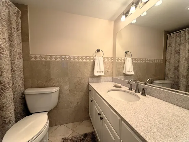 Bathroom featuring a white vanity with an integrated sink, a speckled countertop, and brushed nickel fixtures