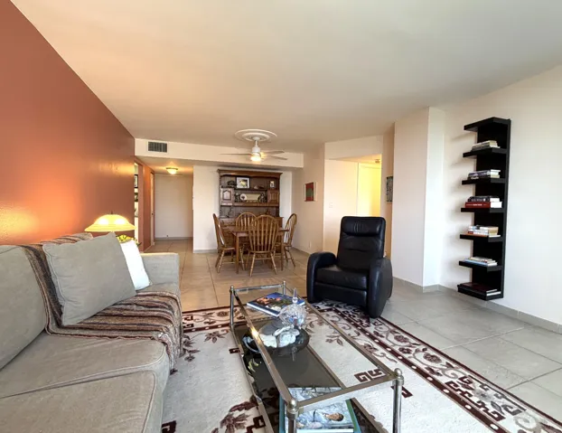 Open-concept living space featuring tile flooring throughout, a ceiling fan with integrated lighting, and a distinctive accent wall