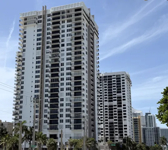 High-rise tower featuring multiple balconies, a white facade, and dark framed windows