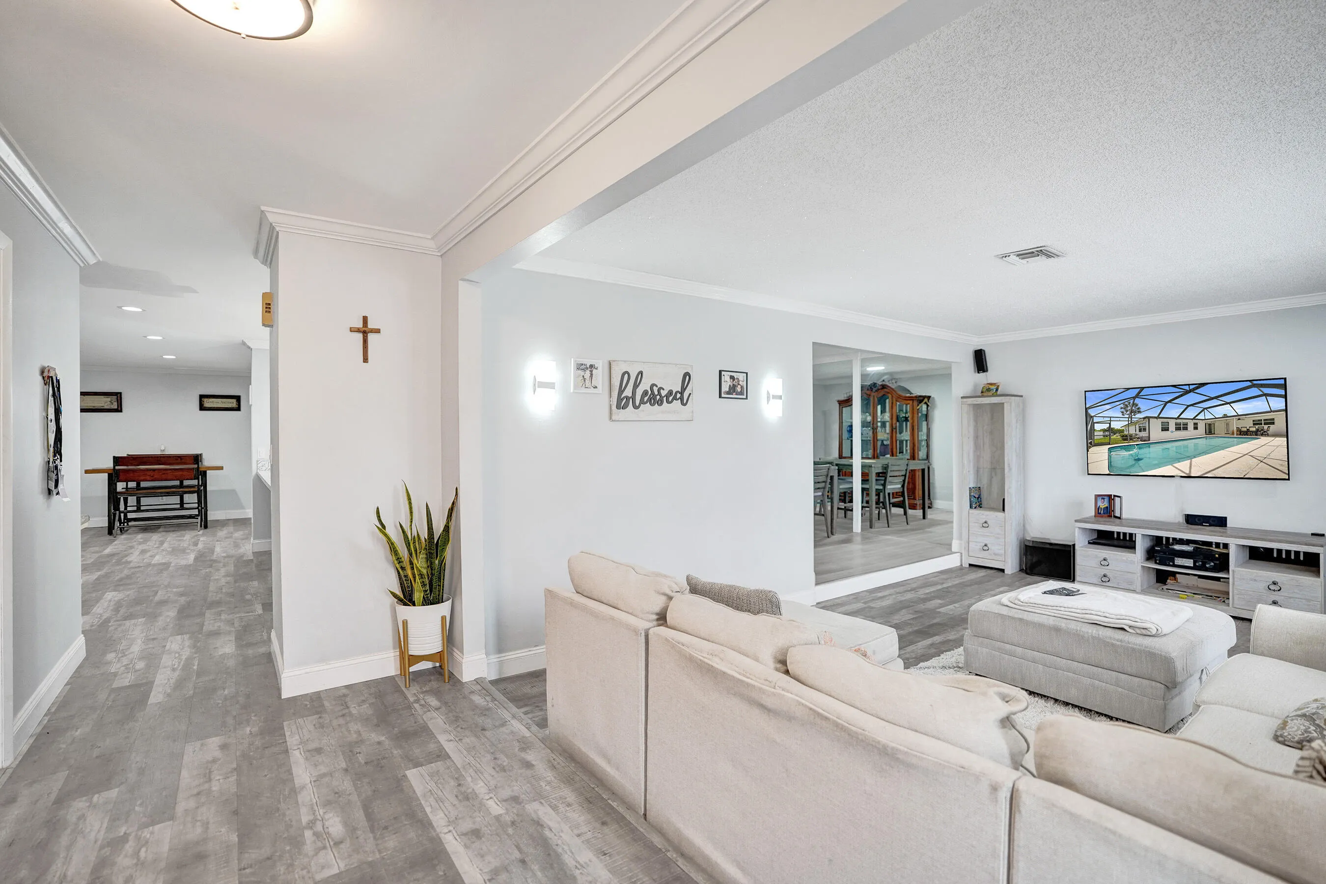 Living area featuring light-toned walls, crown molding, and wood-finish flooring