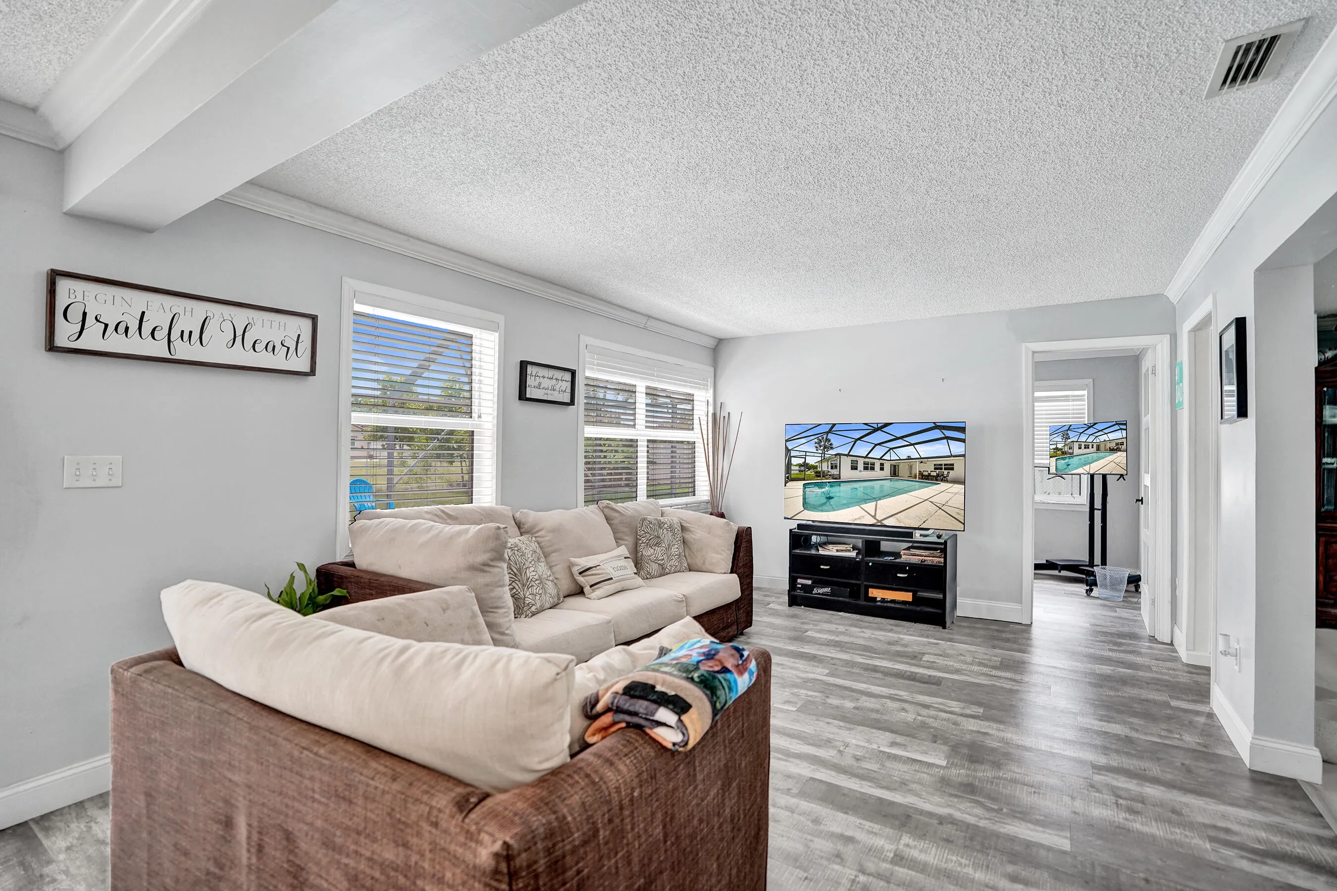 Spacious living area featuring light-toned walls, wood-finish flooring, and white trim