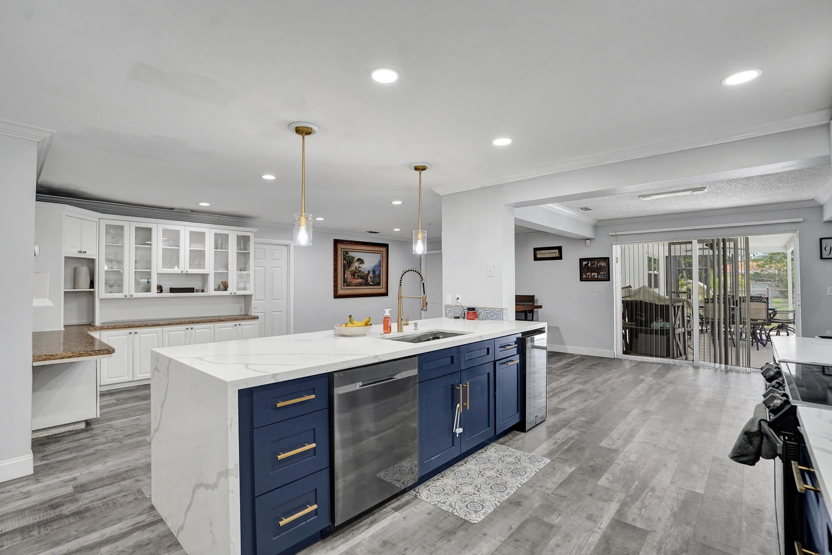 Spacious kitchen featuring a waterfall island with a sink and gold-tone faucet, accompanied by modern blue cabinetry