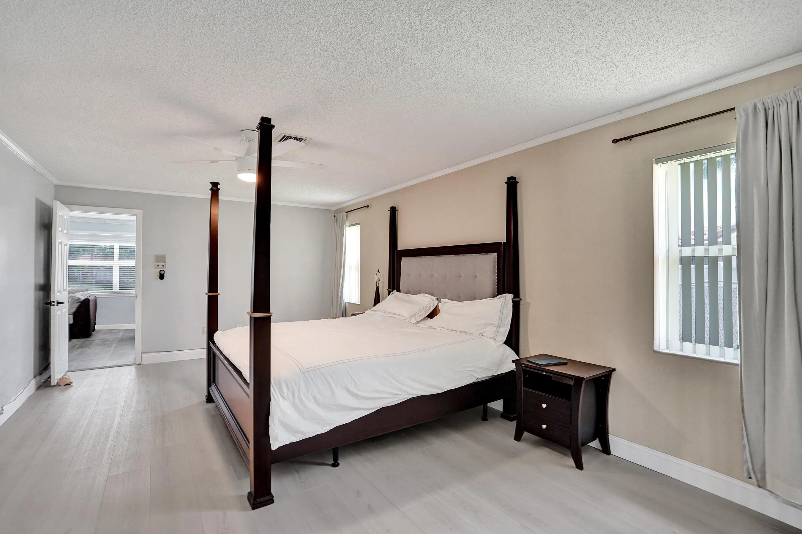 Spacious room featuring light wood-finish flooring, a ceiling fan, and crown molding
