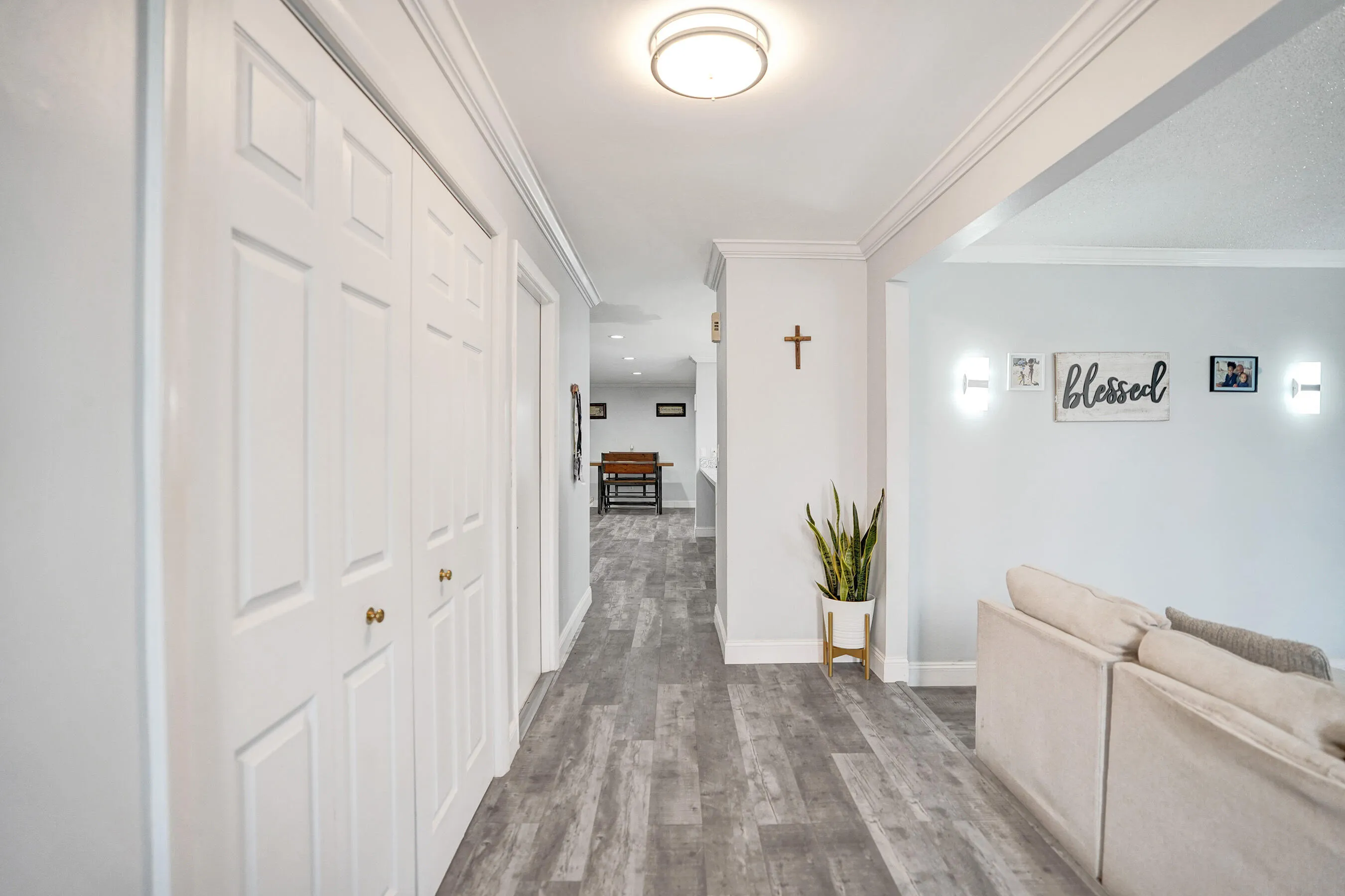 Hallway with wood-finish flooring, white panel bi-fold doors, crown molding, and recessed lighting