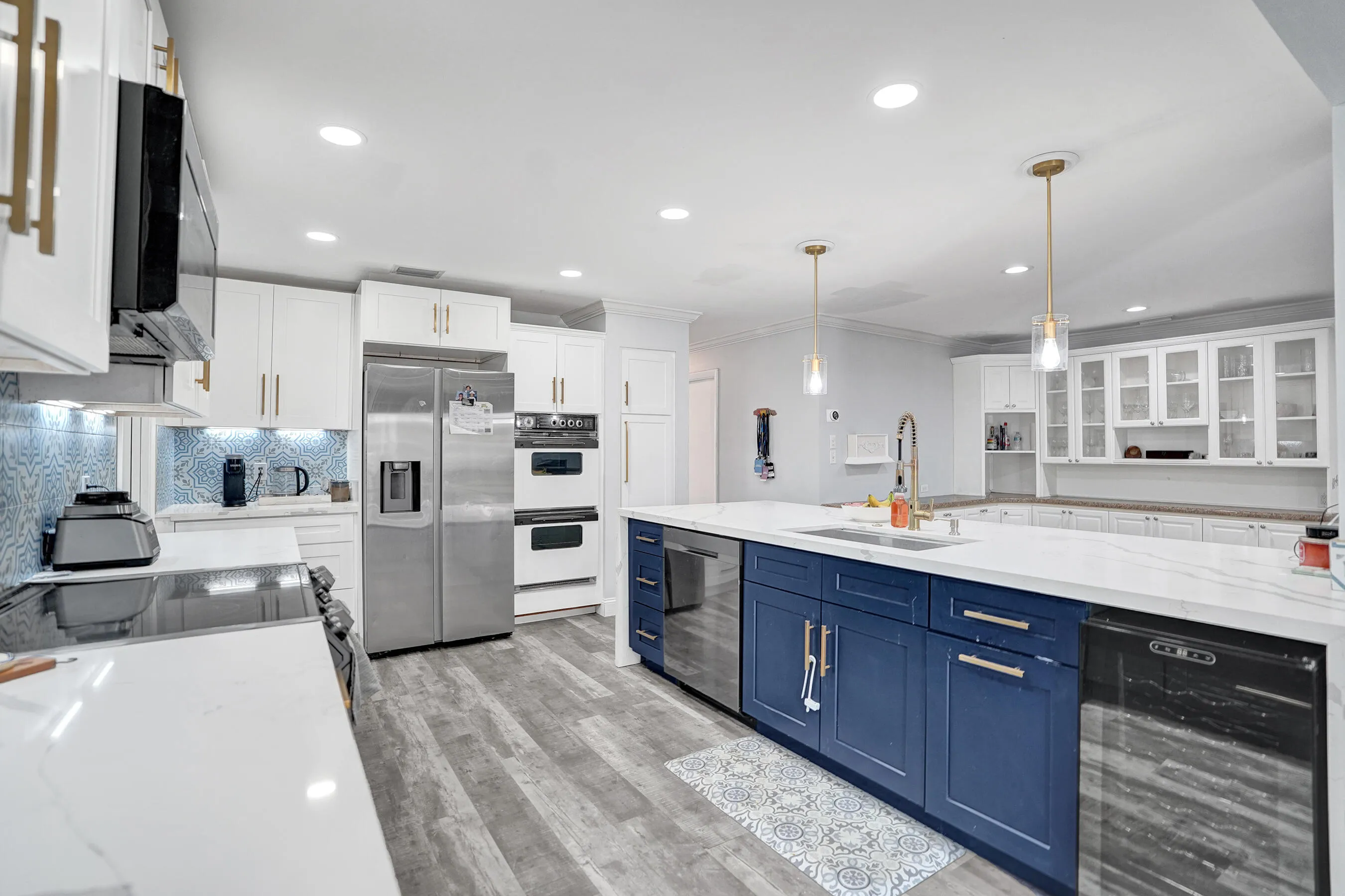 Spacious kitchen featuring a large island with blue cabinetry, white countertops, and stainless steel appliances