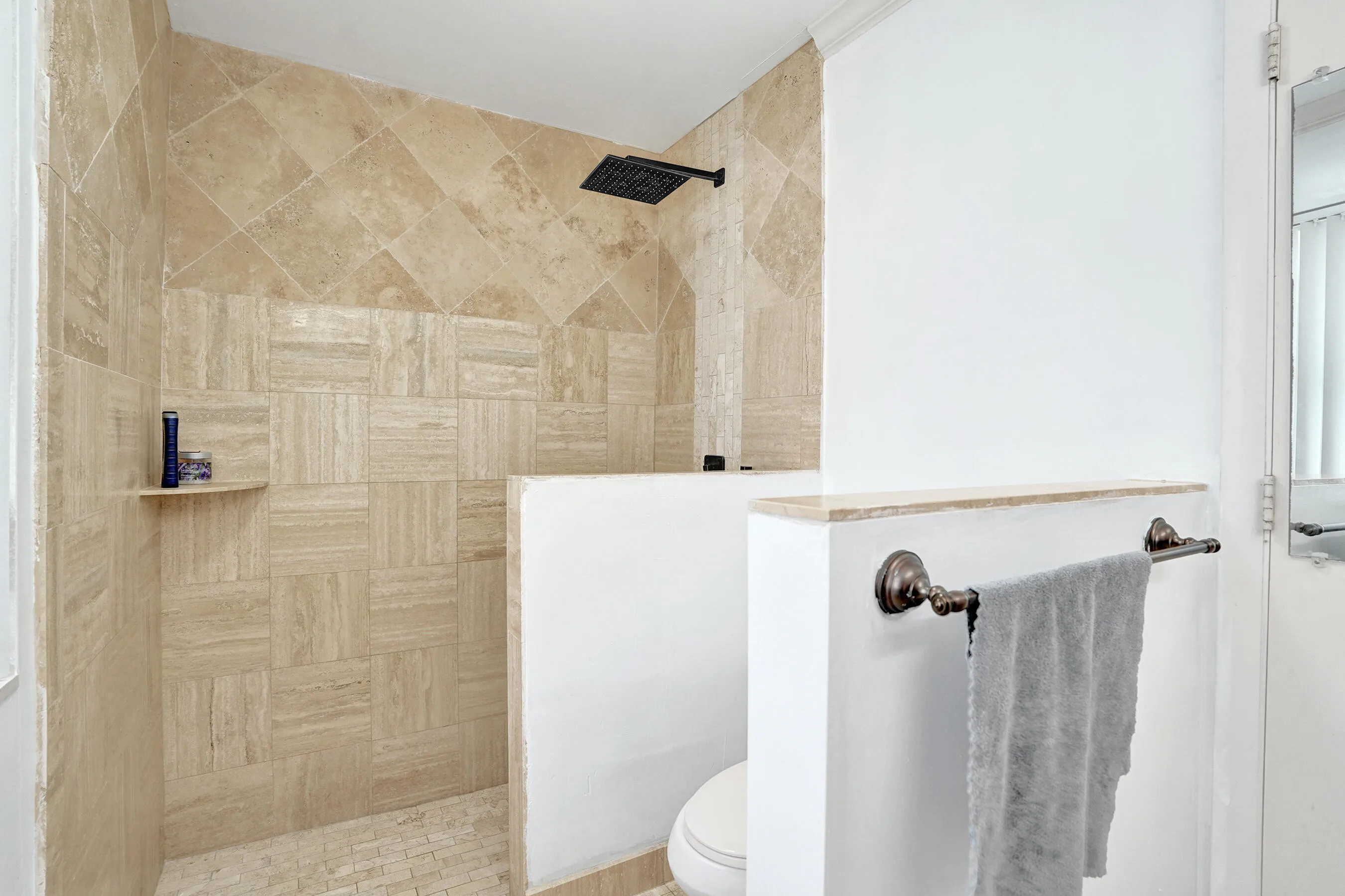 Walk-in shower with natural stone tile surrounds and a square rain showerhead