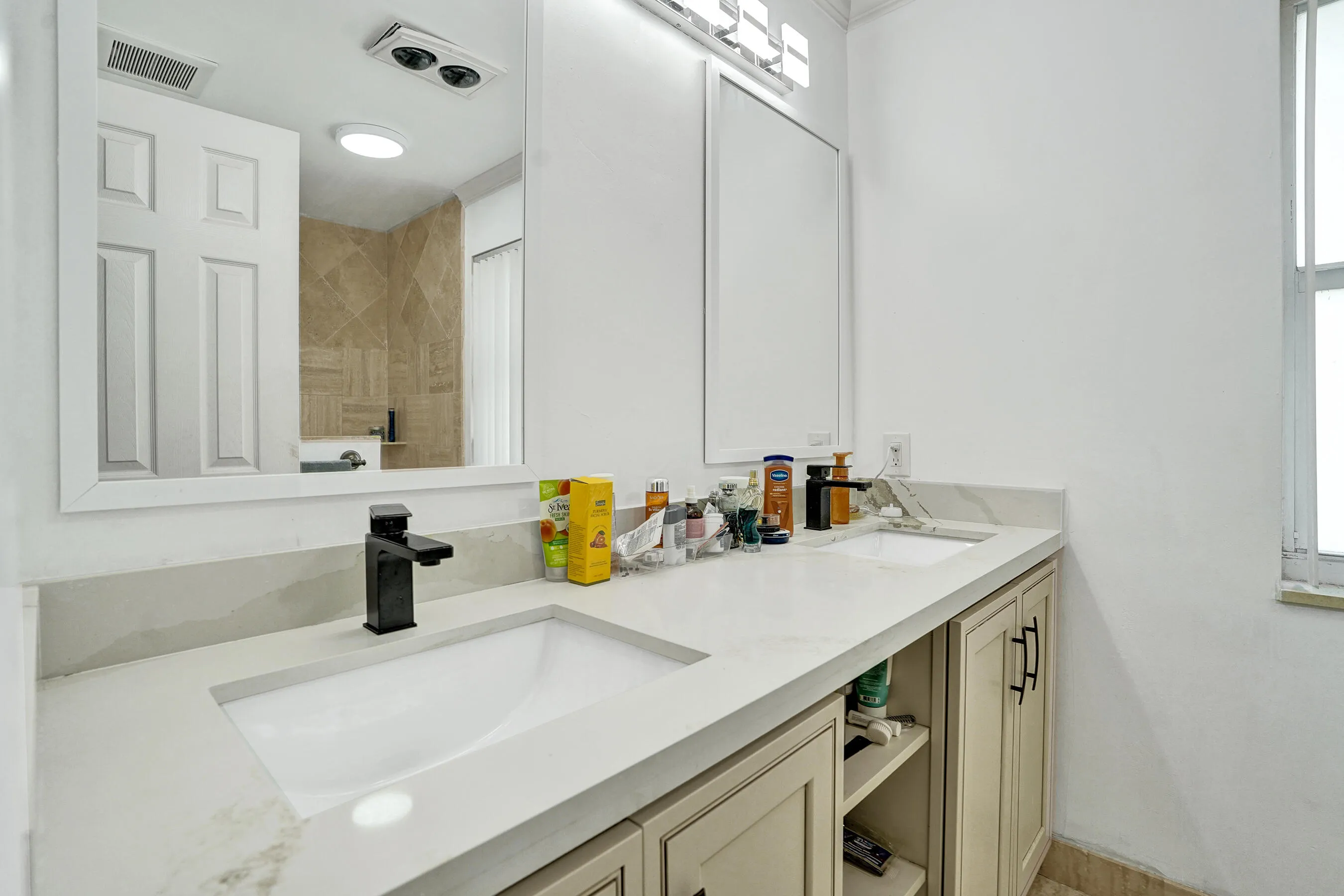 Dual vanity featuring undermount sinks, stone countertops, and matte black fixtures