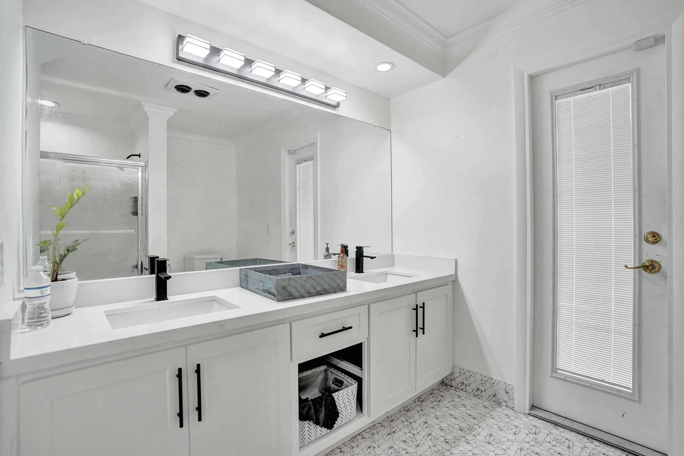 Double vanity with white cabinetry and matte black hardware, featuring integrated sinks and light-colored countertops