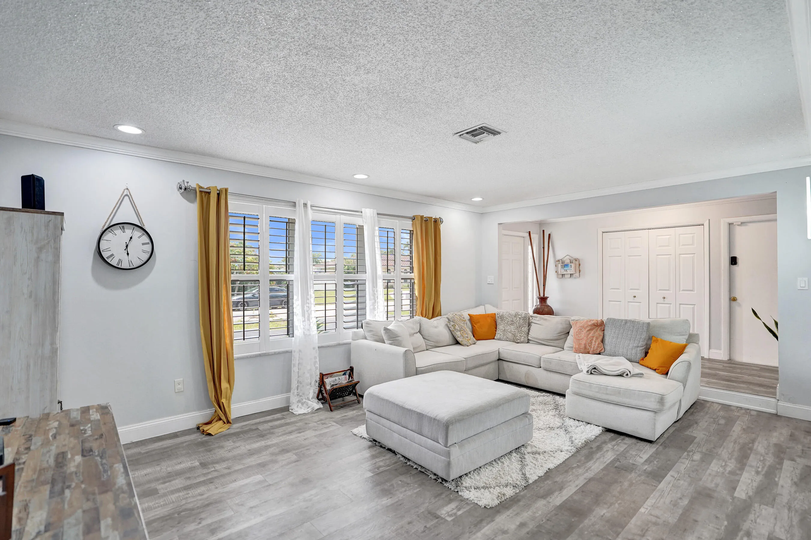 Living area with wood-finish flooring, recessed lighting, and crown molding