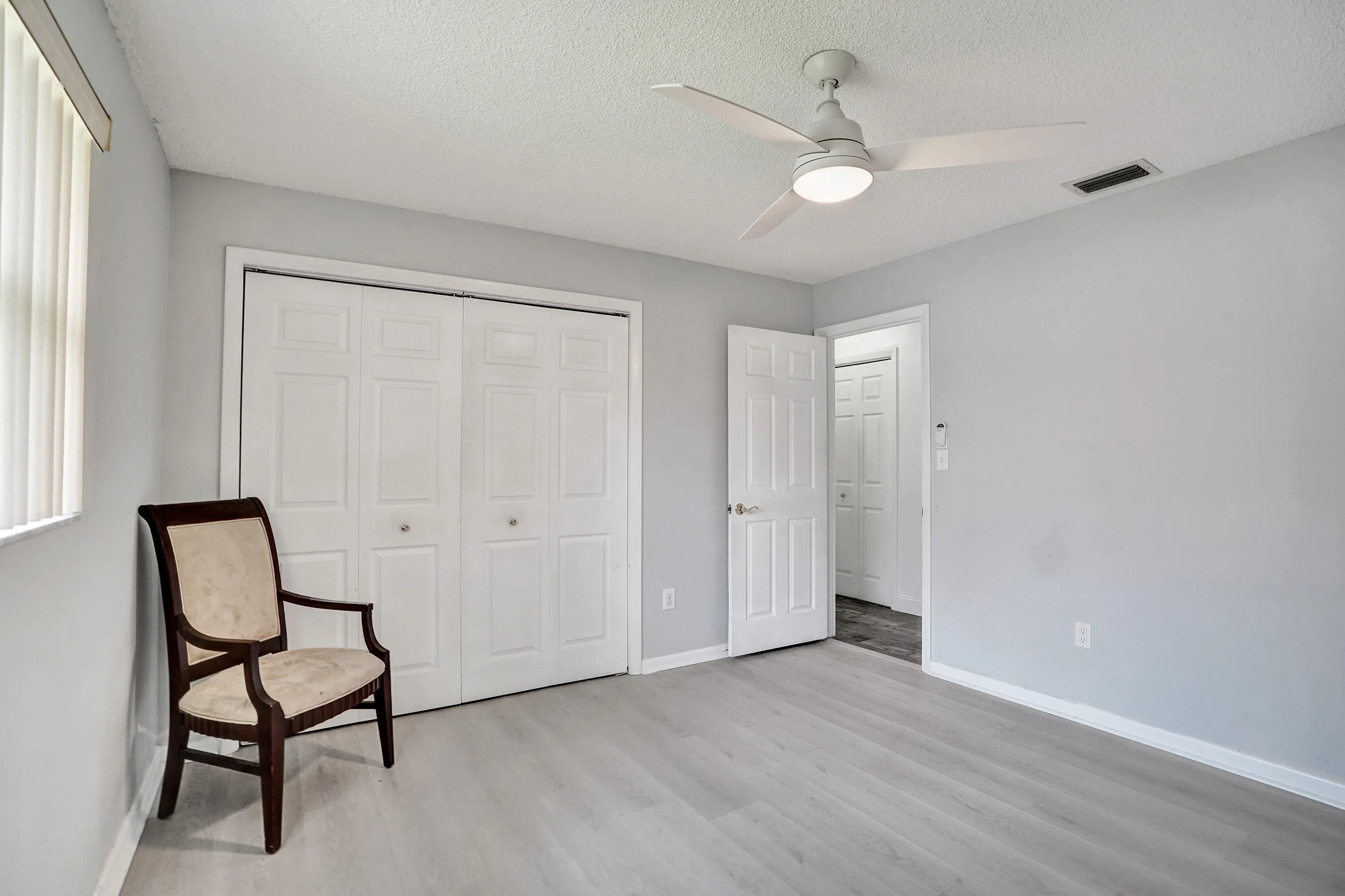 Spacious room featuring light wood-finish flooring, a ceiling fan with integrated lighting, and a double bi-fold closet with panel doors