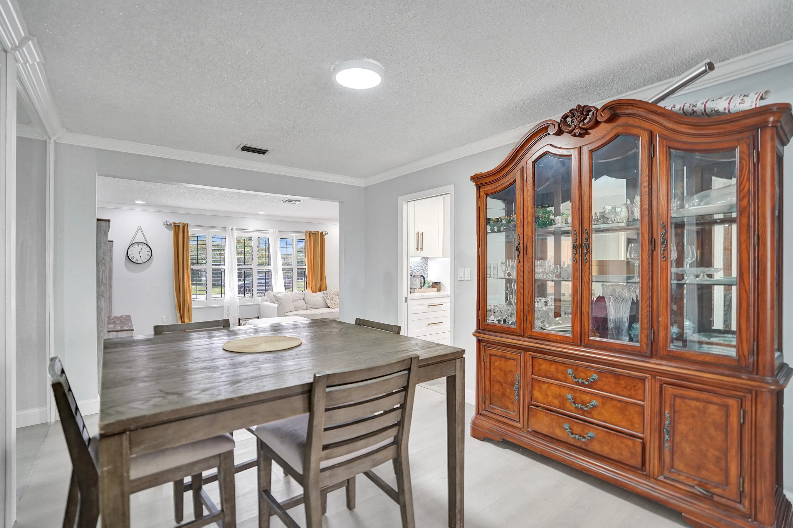 Spacious dining area featuring light-toned flooring, white crown molding, and an open entryway to an additional living space