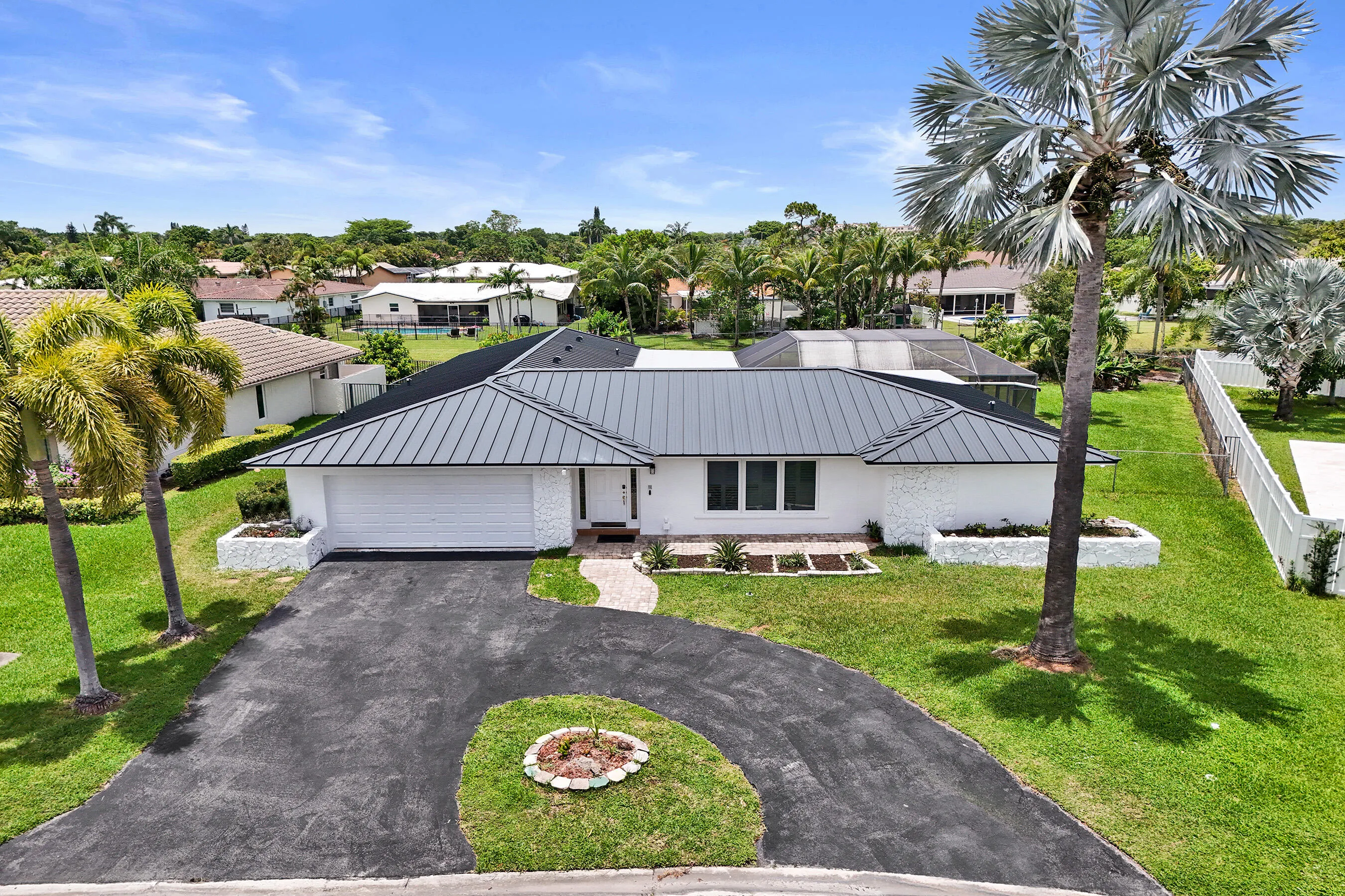 Contemporary single-story residence featuring a gray metal roof and white exterior
