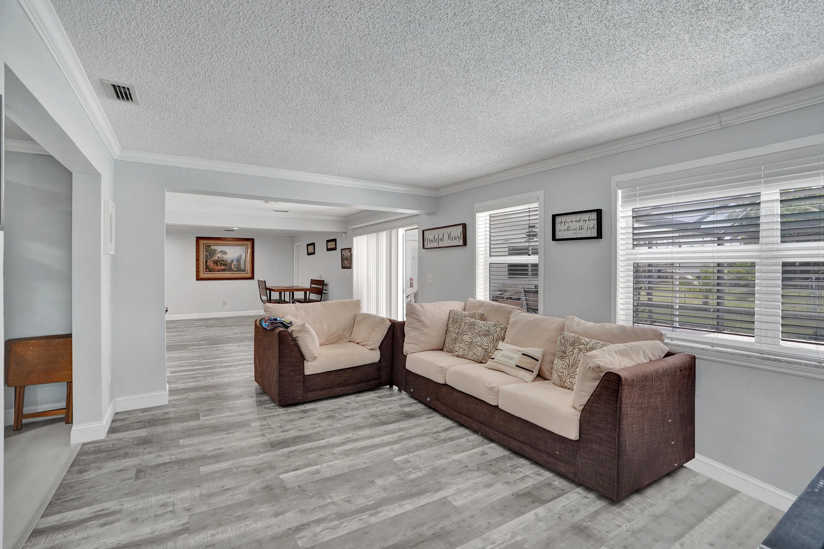 Spacious living area featuring wood-finish flooring, light gray walls, and crown molding