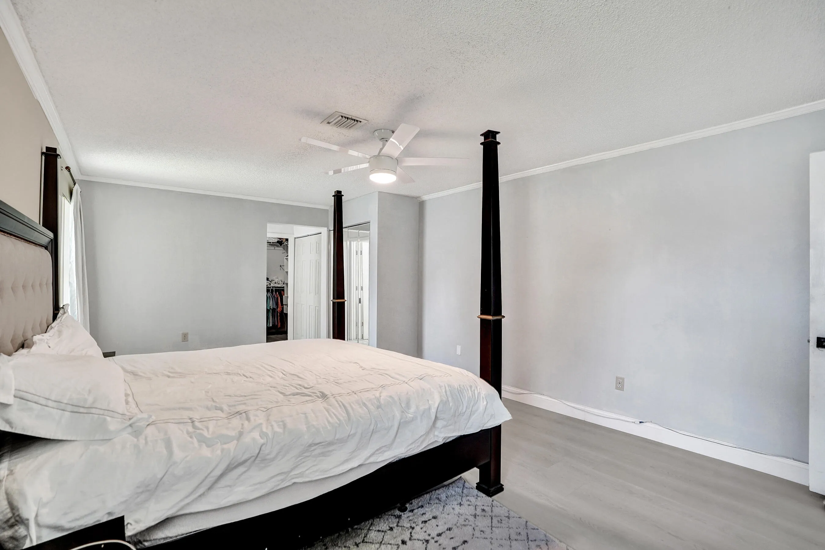 Spacious room featuring wood-finish flooring, crown molding, and a ceiling fan
