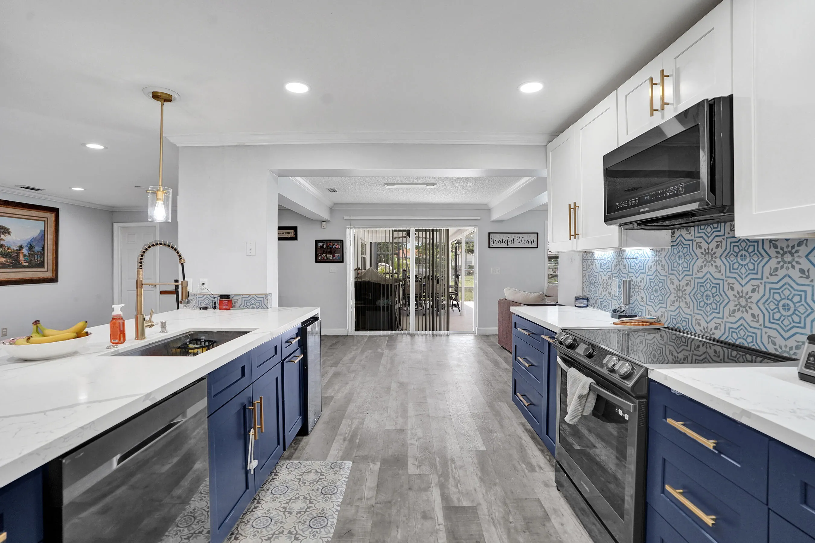 Contemporary kitchen featuring two-tone cabinetry, quartz countertops, patterned tile backsplash, stainless steel appliances, and wood-finish flooring