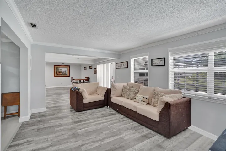 Spacious living area featuring wood-finish flooring, light gray walls, and crown molding