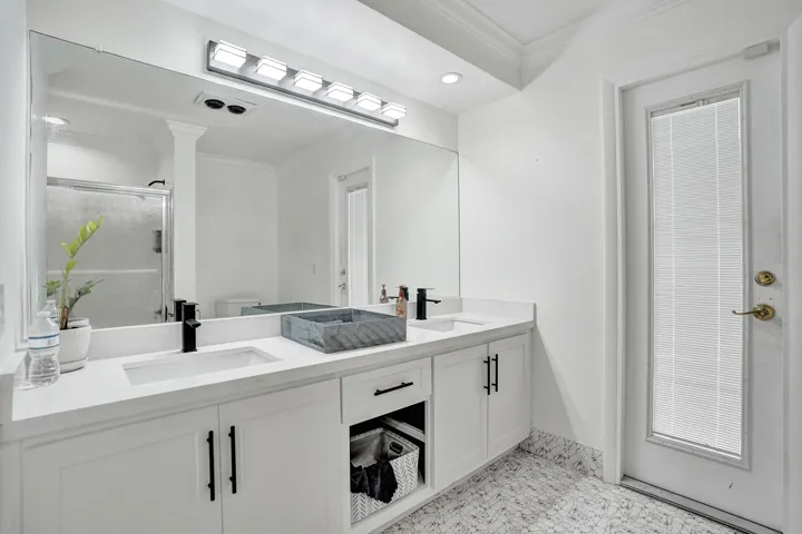 Double vanity with white cabinetry and matte black hardware, featuring integrated sinks and light-colored countertops