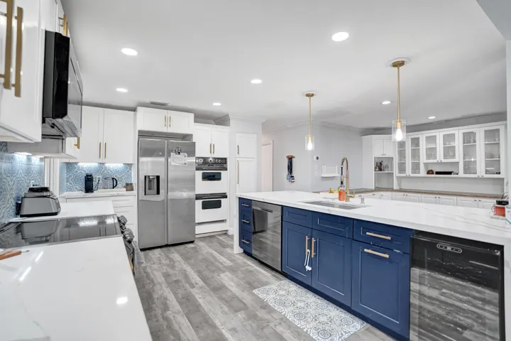 Spacious kitchen featuring a large island with blue cabinetry, white countertops, and stainless steel appliances