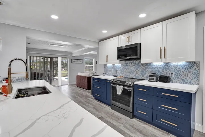Modern kitchen featuring a large island with an undermount sink, quartz countertops, and a gooseneck faucet