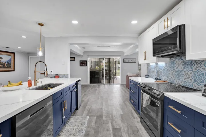 Contemporary kitchen featuring two-tone cabinetry, quartz countertops, patterned tile backsplash, stainless steel appliances, and wood-finish flooring