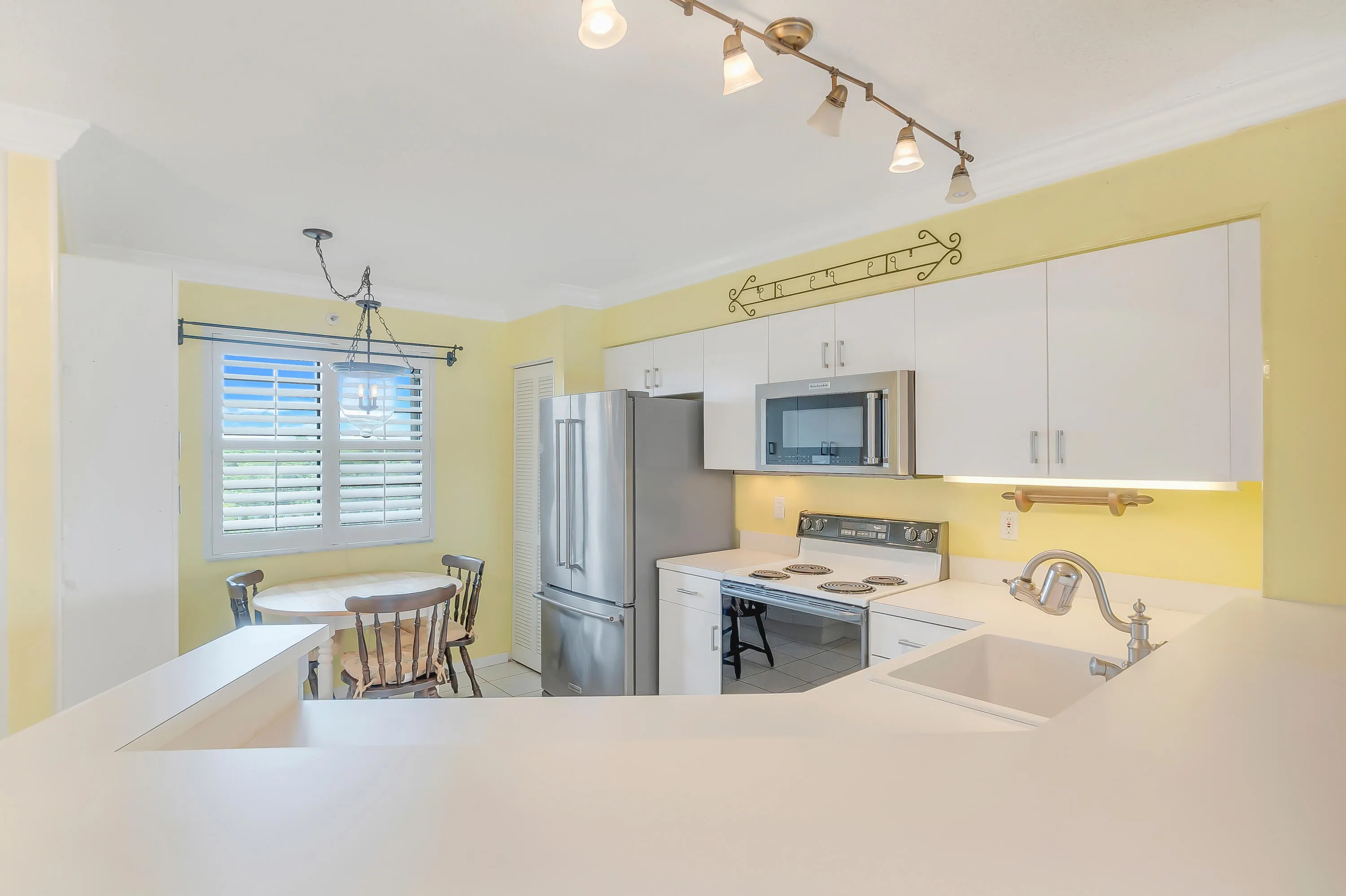 Bright kitchen featuring white cabinetry and countertops, newer stainless steel appliances, and track lighting