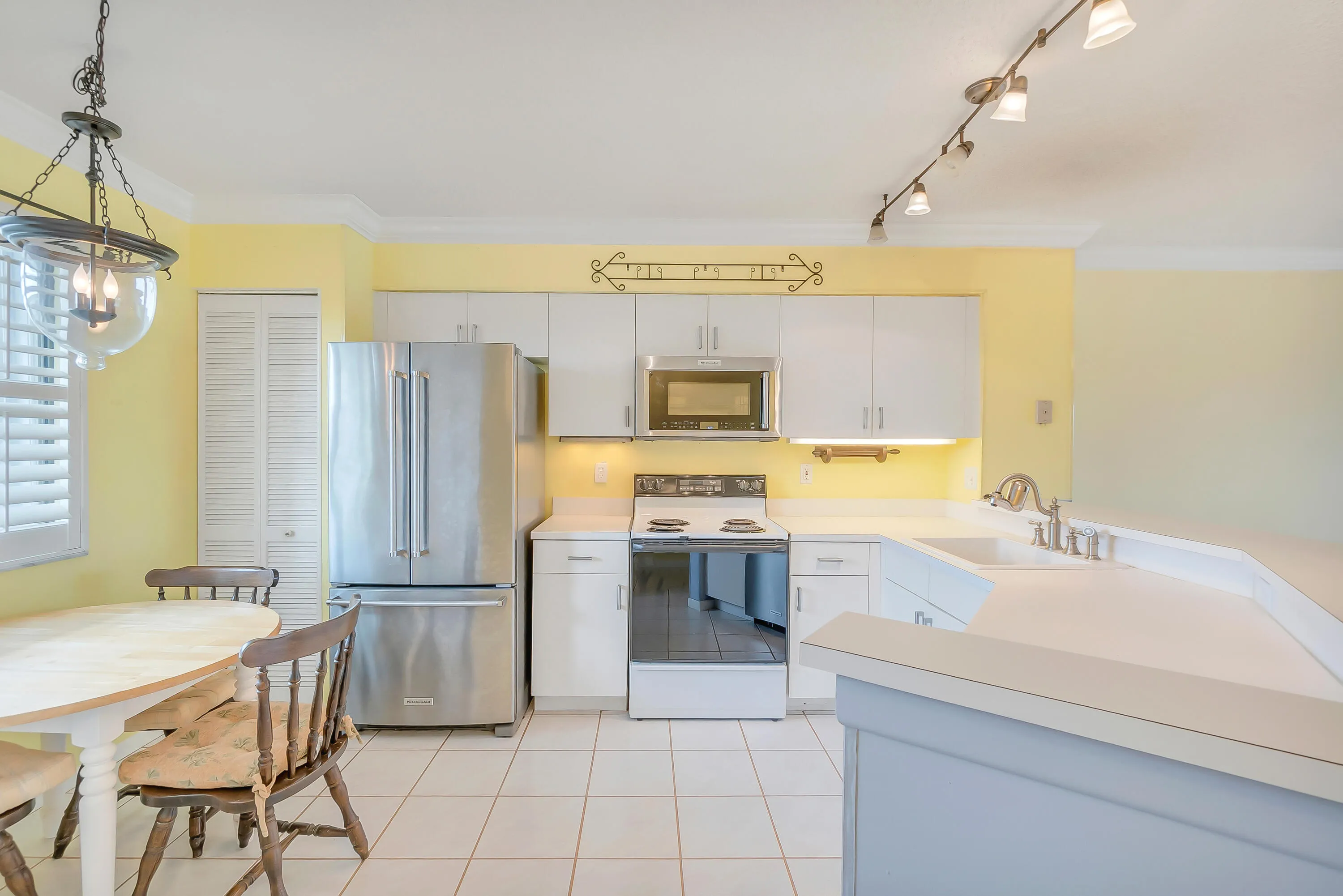 Kitchen featuring white cabinetry and countertops, stainless steel refrigerator, dishwasher and microwave.