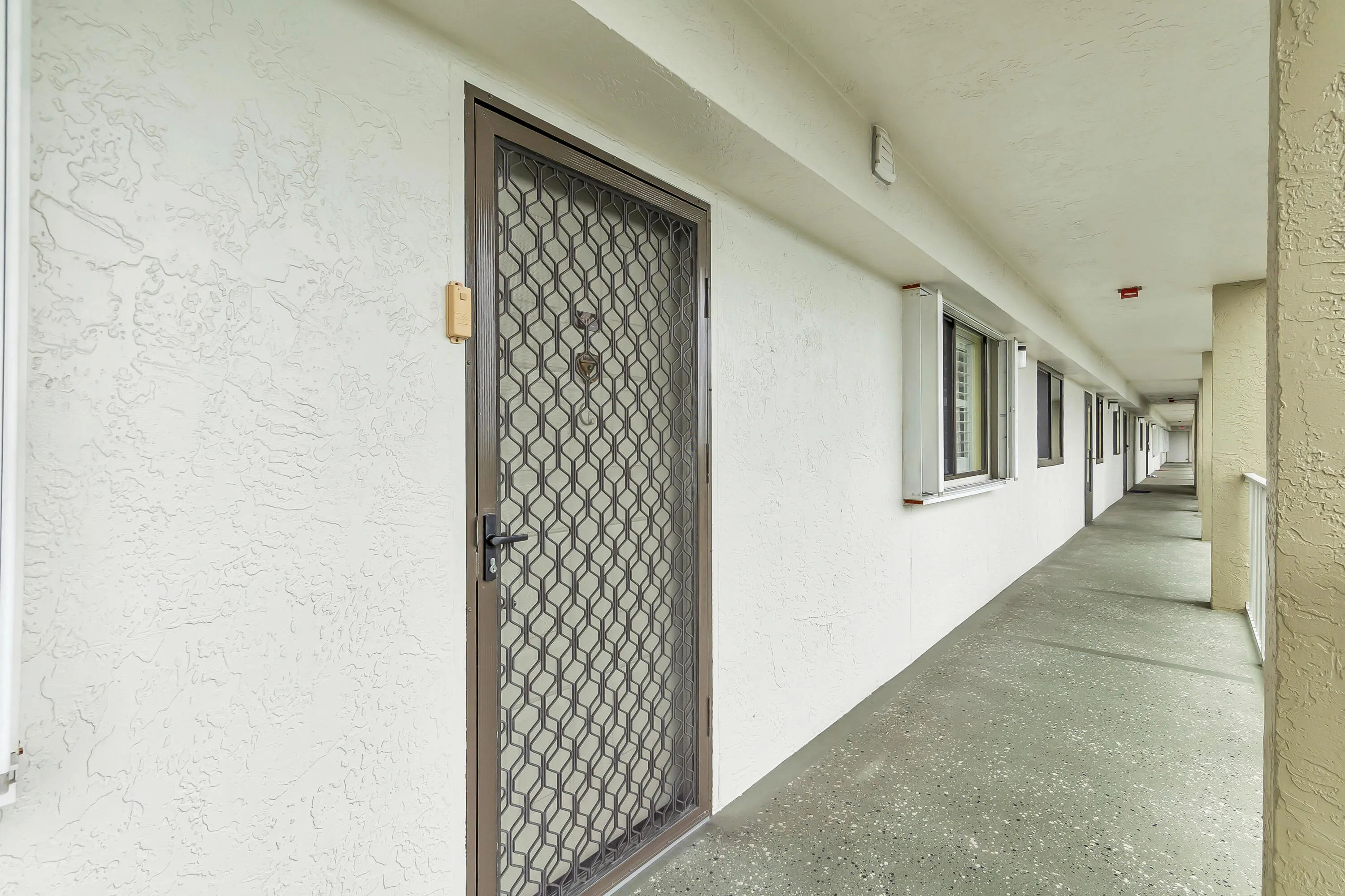Brown metal screened security door with an abstract geometric pattern