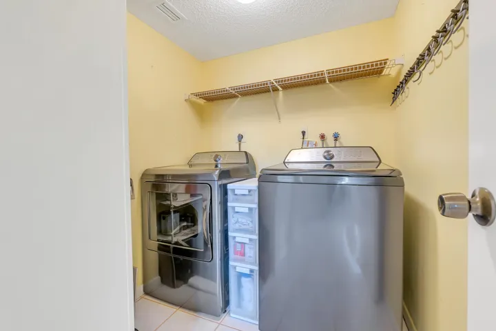 Dedicated utility space featuring newer over-sized washer/dryer, tile flooring and lots of shelving