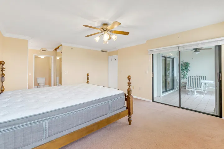 Carpeted room featuring a ceiling fan with light fixture, crown molding, and a sliding glass door opening to the tiled outdoor patio.