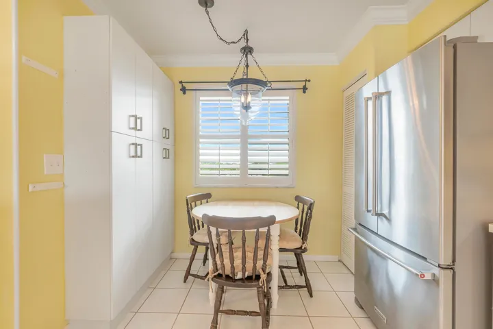 Bright kitchen area featuring white cabinetry, a stainless steel French-door refrigerator, and a window with plantation shutters.