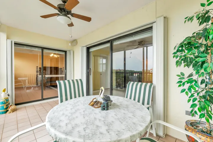 Tiled outdoor patio with a ceiling fan and full accordion hurricane shutters
