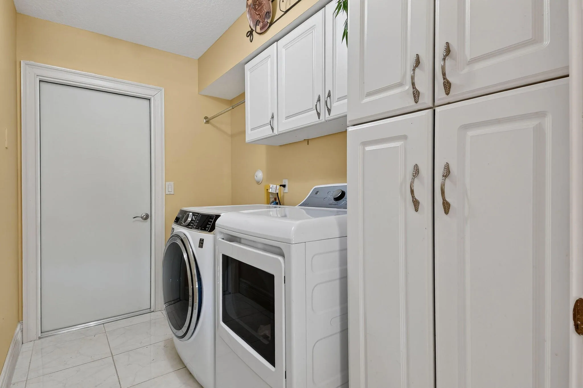 Laundry room with cabinets for storage, Sink. Entrance to the 2-car garage.