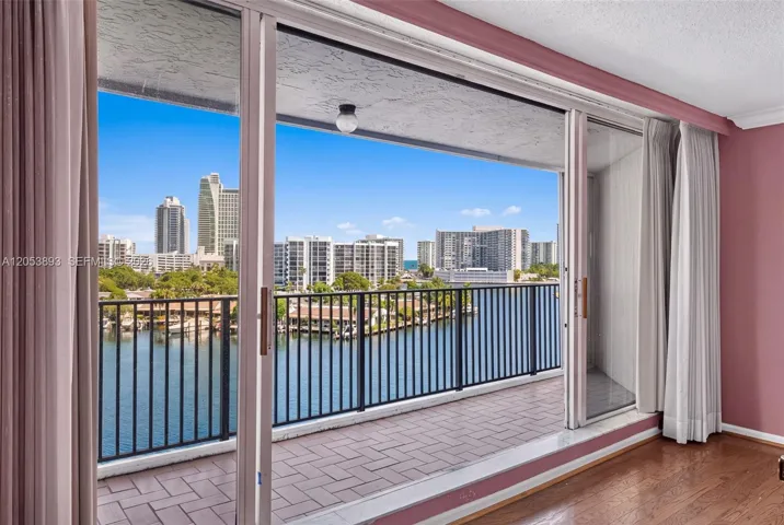 Covered balcony featuring herringbone-patterned tile flooring, black metal railing, and floor-to-ceiling sliding glass doors