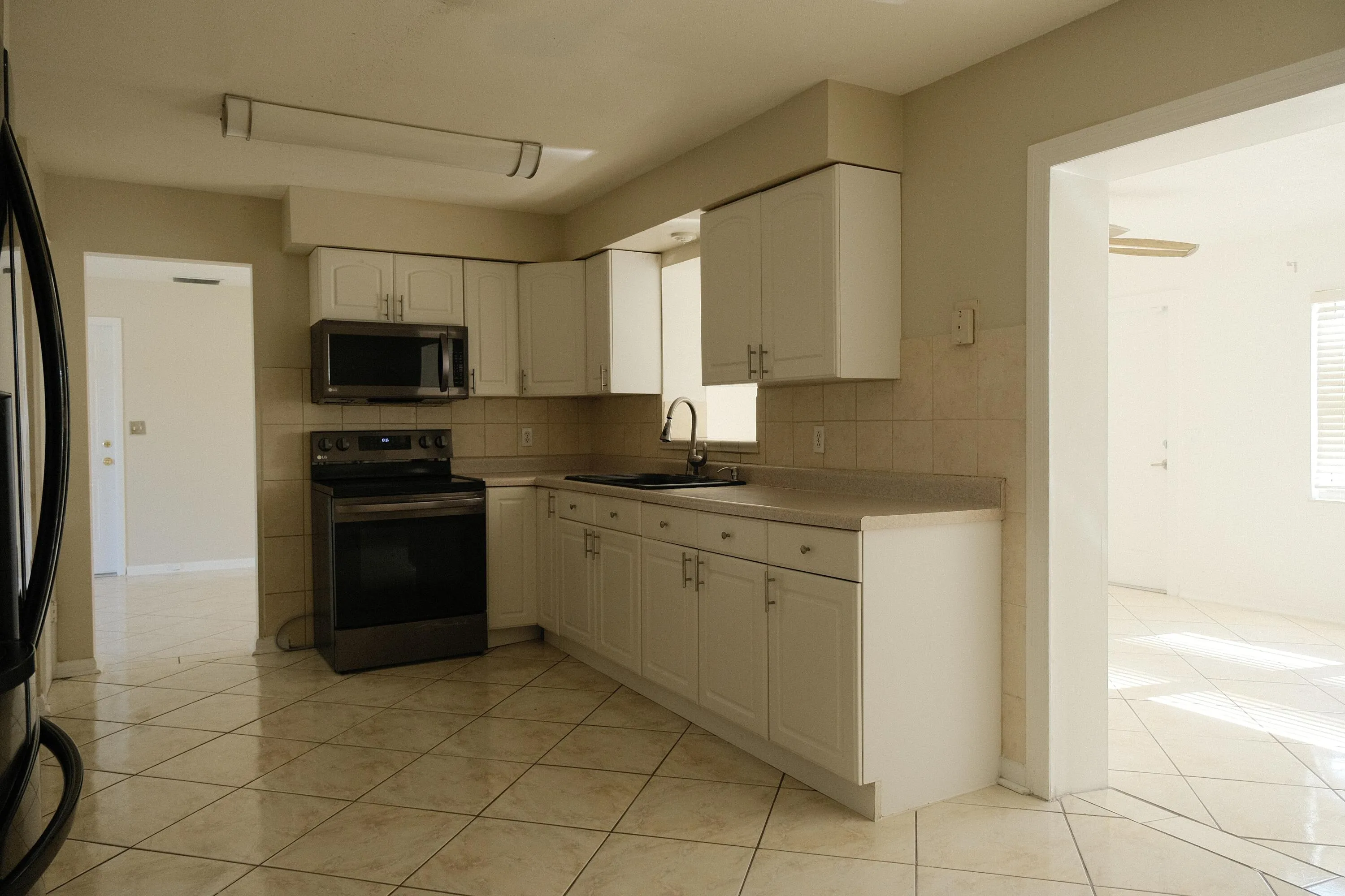 White cabinetry with brushed nickel hardware, stainless steel microwave, and range