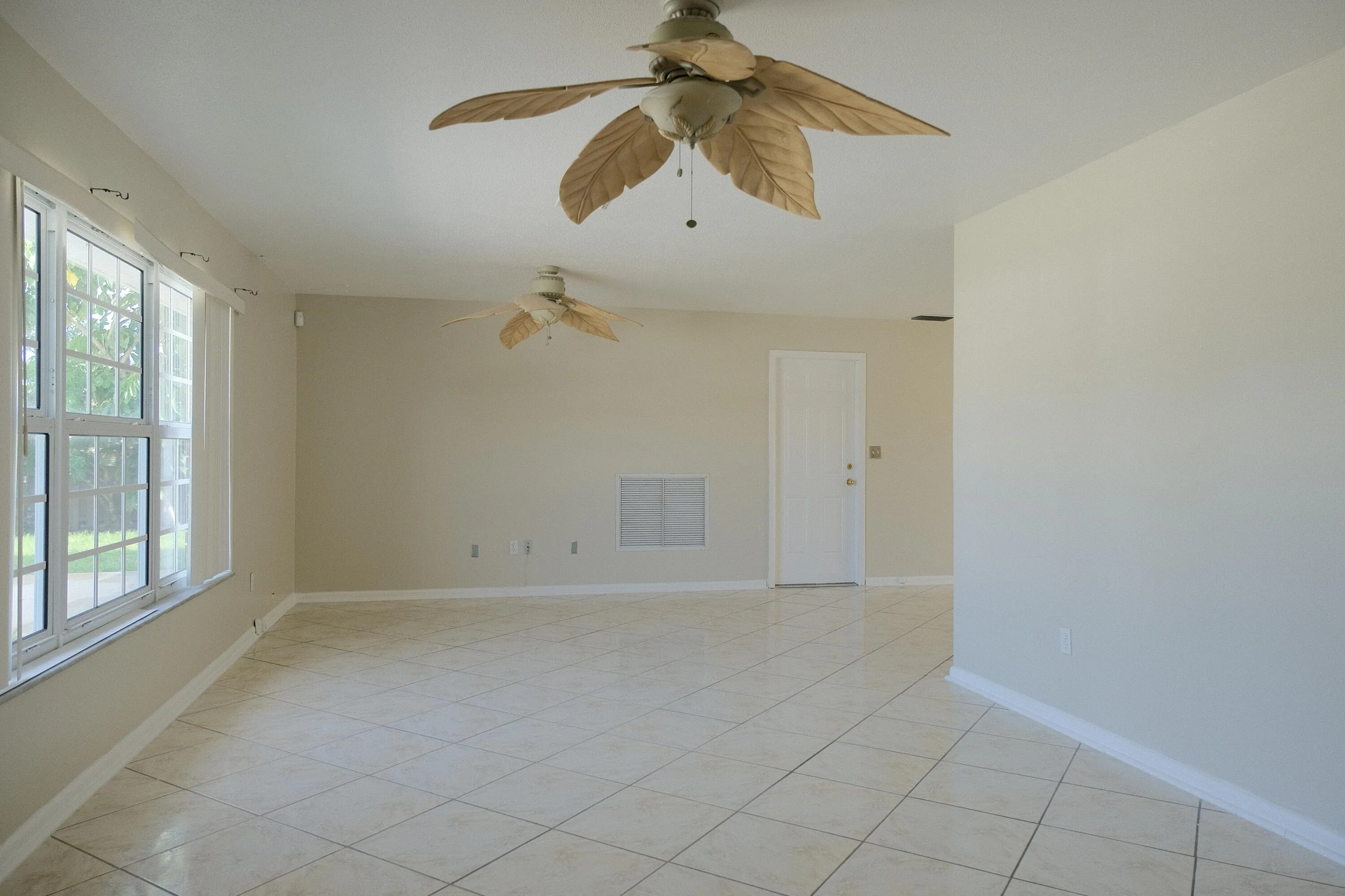 Spacious interior featuring neutral tone walls, diagonal tile flooring, and multiple windows with white grid panes
