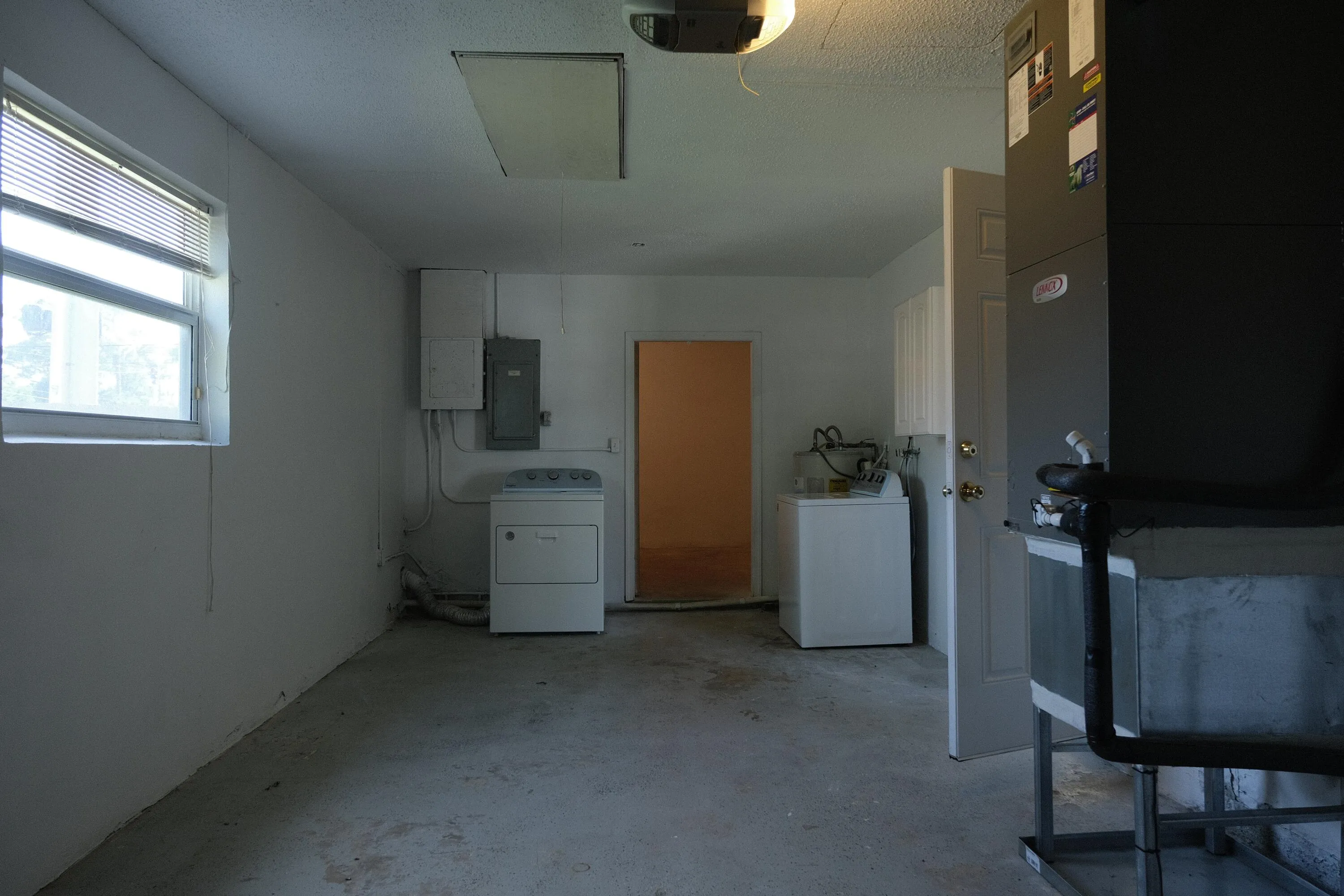 Utility room featuring a concrete floor, window with blinds, and white painted walls