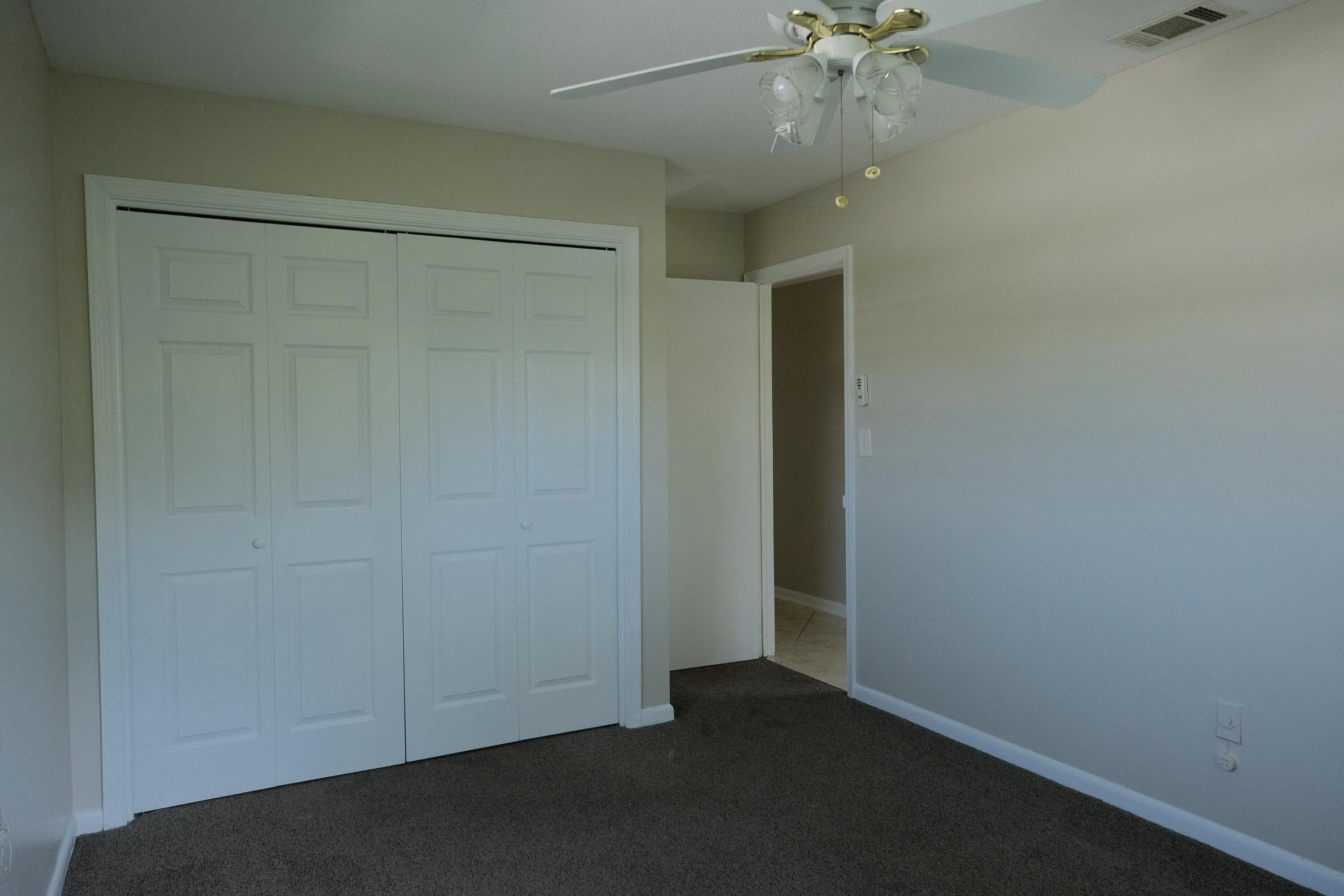 Neutral-toned room featuring a four-panel bi-fold closet, ceiling fan with integrated lighting, and carpet flooring